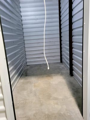 A white cord is hanging from the ceiling in a storage unit.